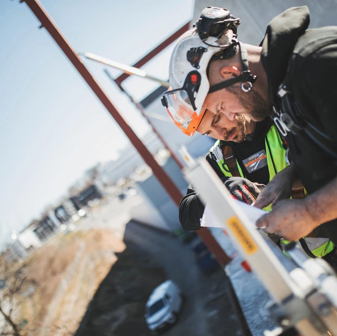 Två kollegor från Komstasmén går igenom ritningar på byggplatsen
